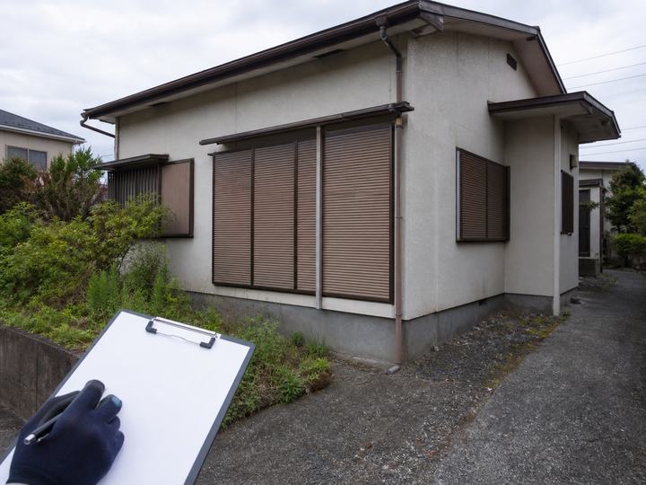 空き家の外壁や雨どいを記録しながら確認する様子